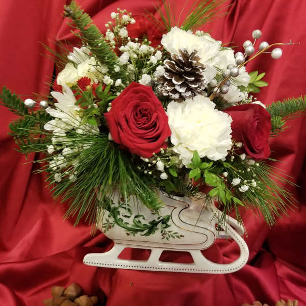 Red and white floral arrangement in a white sleigh container