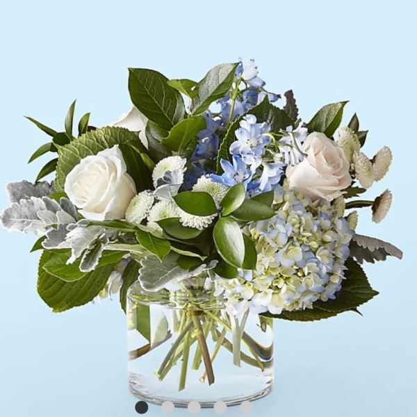 White roses and blue hydrangea in a clear glass vase