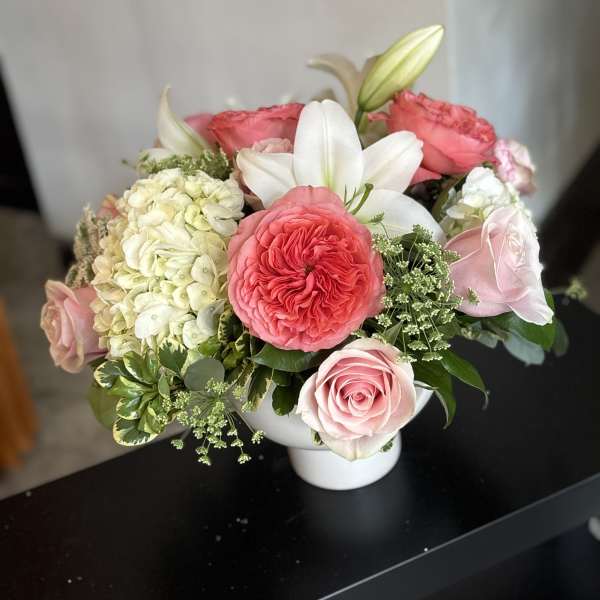 Pink and white rose arrangement with a white lily in a vase