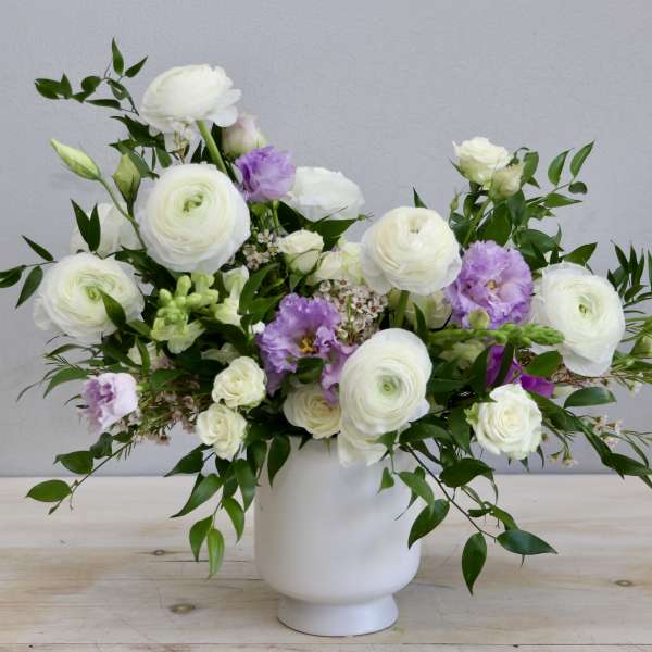 White and light purple flower arrangement in a matte white vase