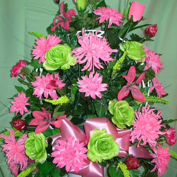Pink and green floral arrangement in a white pot with a pink ribbon