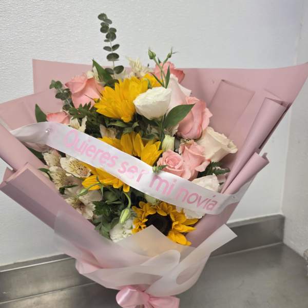 Pink-wrapped bouquet with sunflowers, pink roses, and a white ribbon