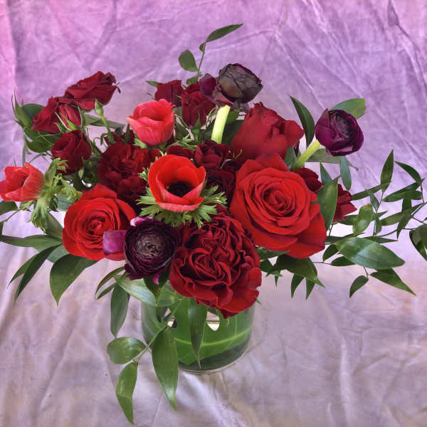 Red roses and dark ranunculus in a glass vase