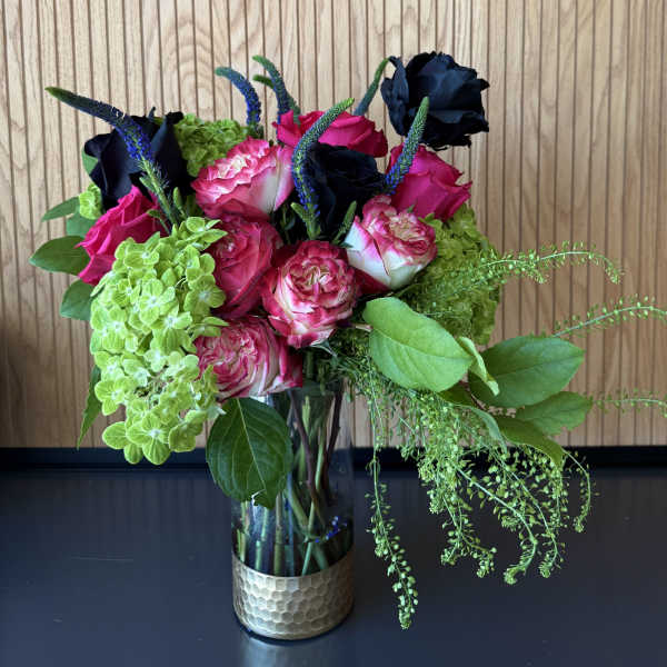 Bouquet of pink and dark roses with green hydrangeas in a glass vase