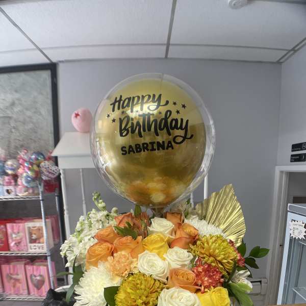 Birthday flower arrangement with a gold balloon in a black hatbox