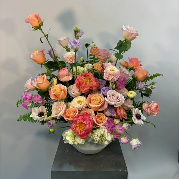 Large pastel floral arrangement in a white bowl vase
