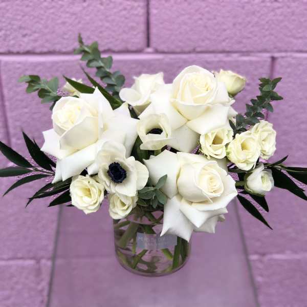White roses and calla lilies in a clear glass vase