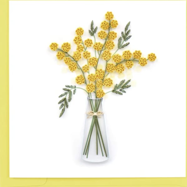 Yellow pom-pom flowers in a clear glass vase with a small bow
