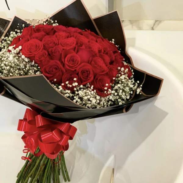 Bouquet of red roses with white baby's breath in black wrap