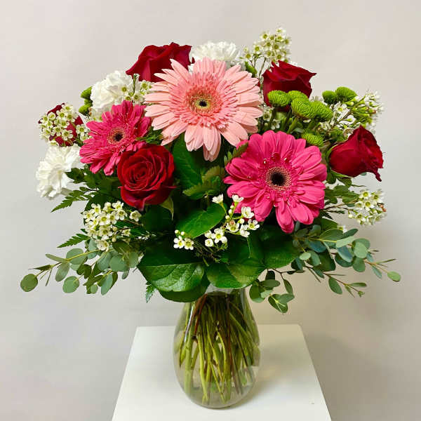 Bouquet of pink gerbera daisies and red roses in a glass vase