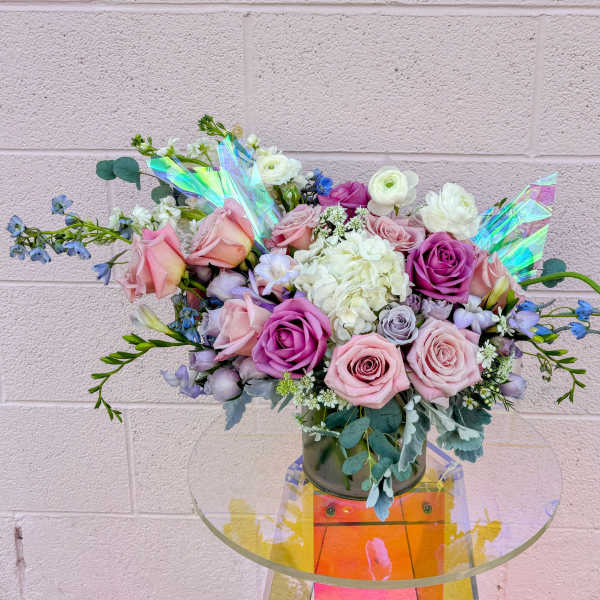 Bouquet of pink and purple roses with white blooms in a glass vase