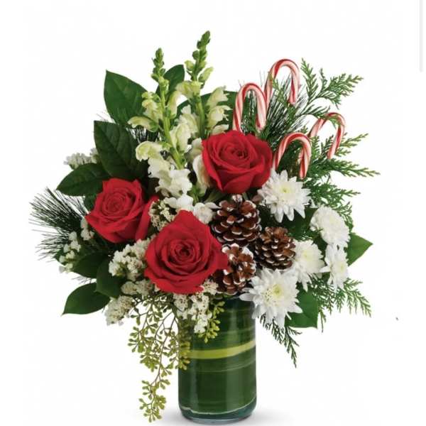 Red roses and white flowers in a green glass vase with candy canes and pinecones