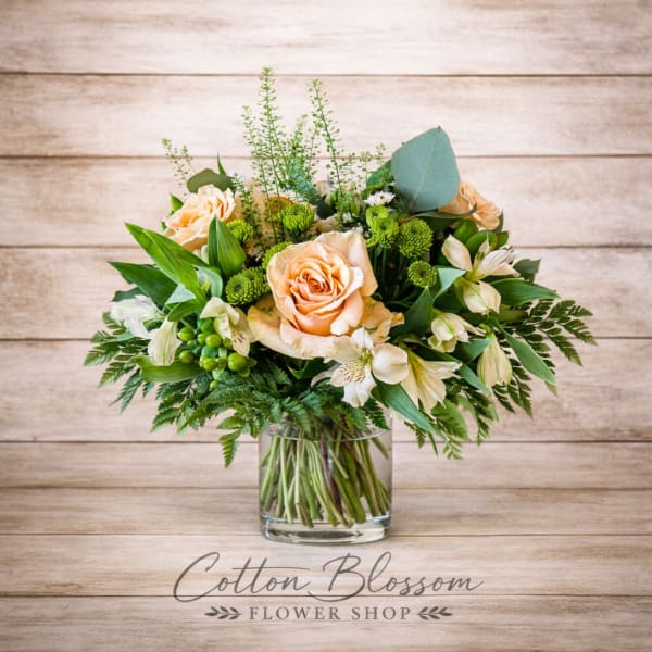 Peach roses and white alstroemeria in a clear glass vase