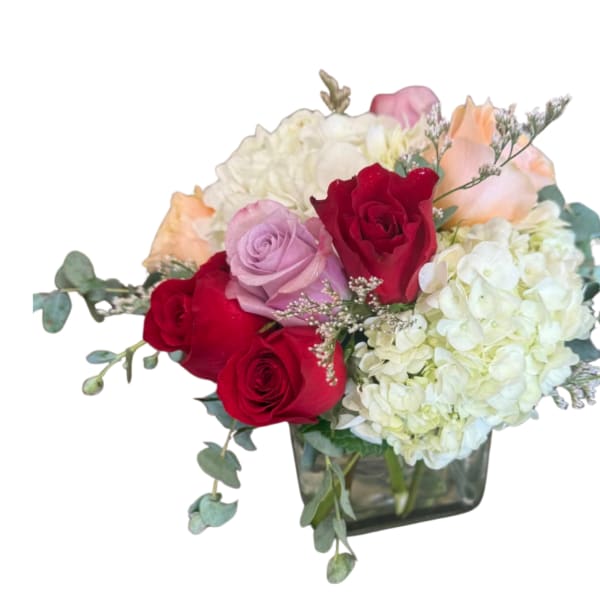 Mixed bouquet of red and pink roses with white hydrangeas in a glass vase