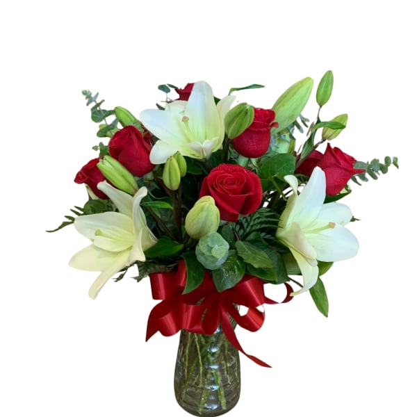 Red roses and white lilies in a glass vase with a red ribbon