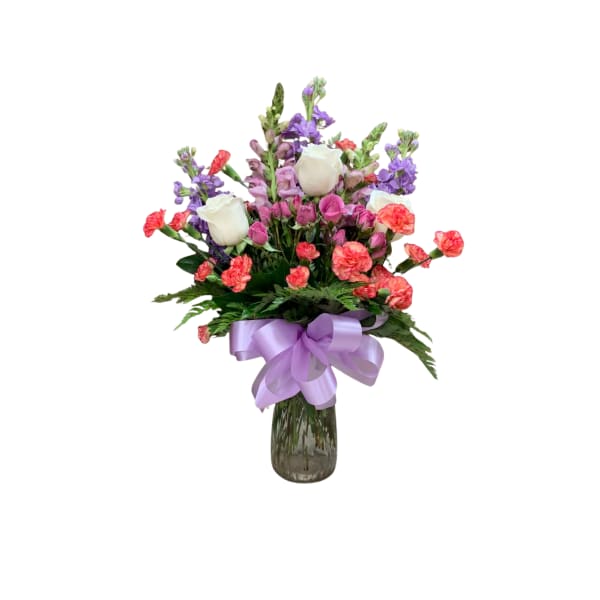 Bouquet of white roses, pink carnations, and purple flowers in a glass vase