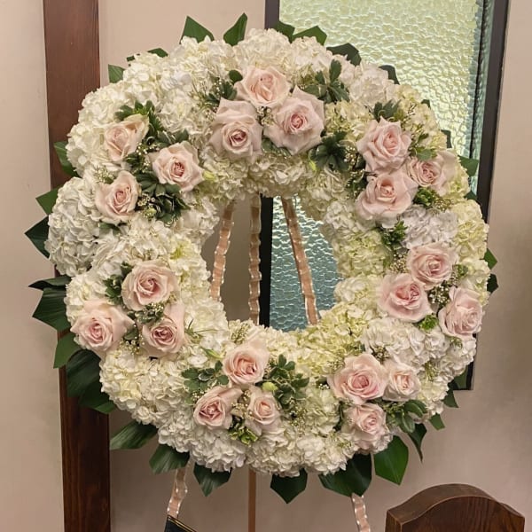 Large white floral wreath with pale pink roses on an easel