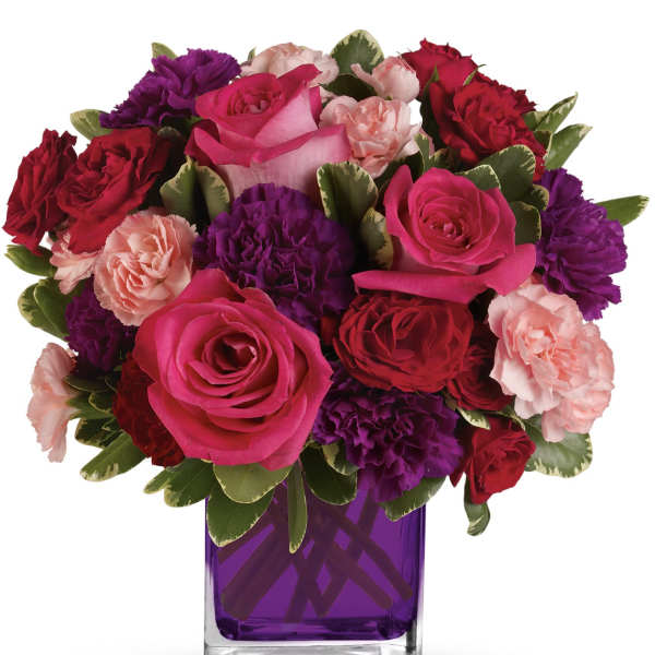 Bouquet of pink, red, and purple flowers in a purple glass vase