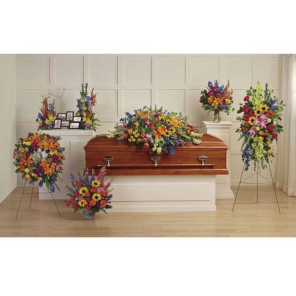Colorful funeral casket spray with standing floral arrangements