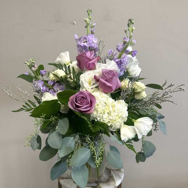 Lavender and white floral arrangement in a vase with trailing eucalyptus