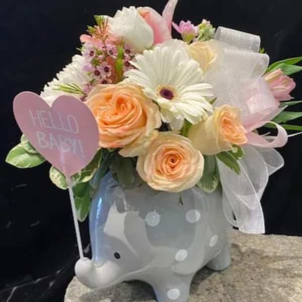 Pastel flower arrangement in a gray elephant planter with a pink heart sign