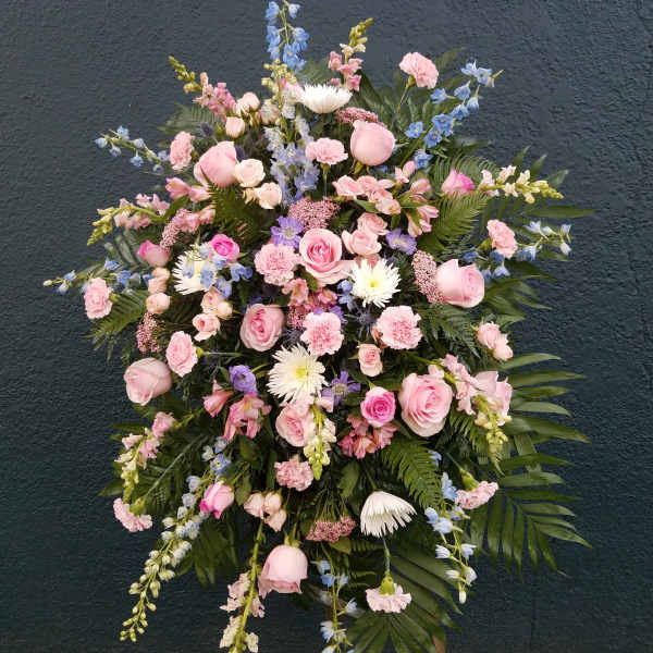 Large standing spray of pink and blue flowers on a dark wall