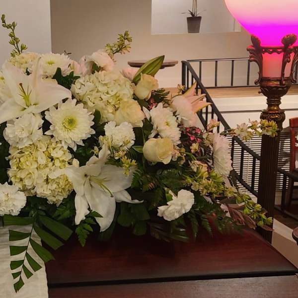 Large white floral arrangement with lilies, daisies, and hydrangeas