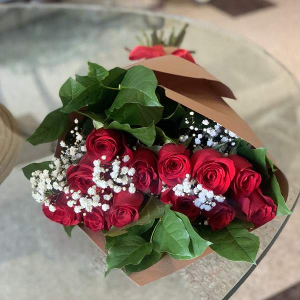 Bouquet of red roses with white baby's breath in brown paper