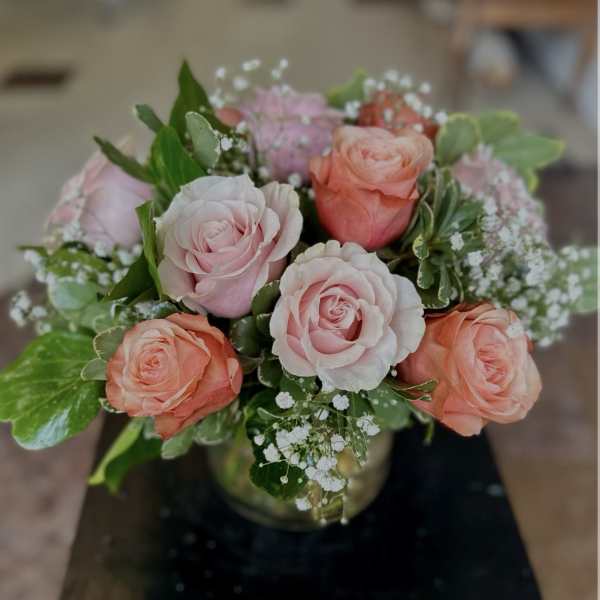Pink and peach roses arranged in a glass vase