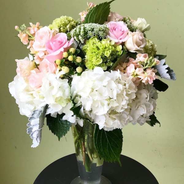 Bouquet of pink, white, and green flowers in a clear glass vase