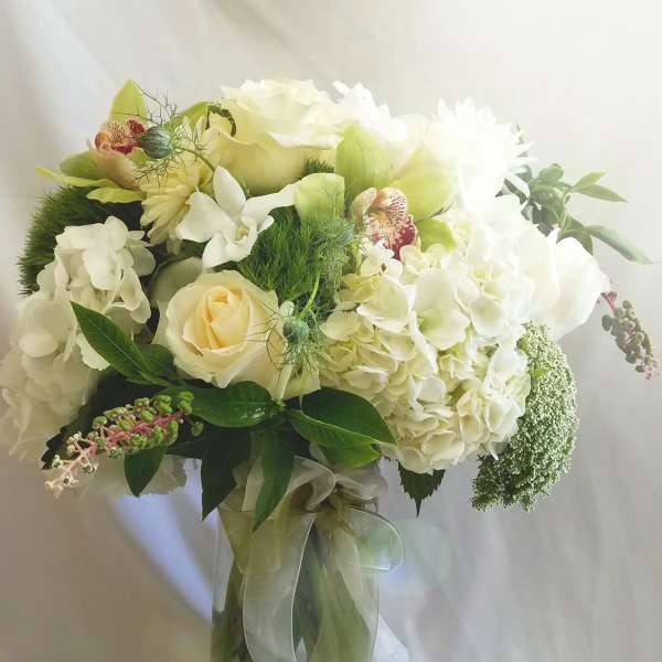 White floral bouquet in a glass vase with a ribbon tie
