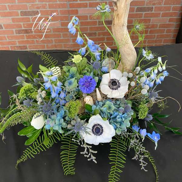 Blue and white floral arrangement with driftwood and shells
