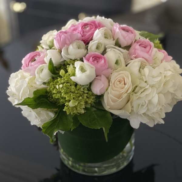 Pink and white flowers arranged in a round glass vase