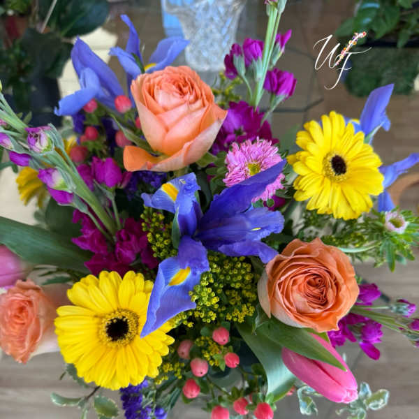 Colorful bouquet with peach roses, yellow gerbera daisies, and blue irises
