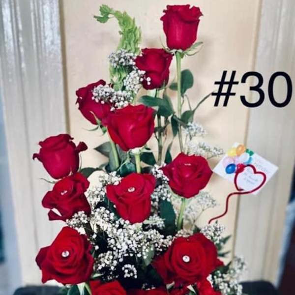 Tall arrangement of red roses with baby's breath in a white container