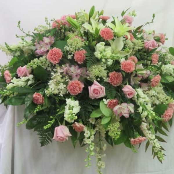 Large horizontal spray of pink roses and carnations with white lilies and other white flowers