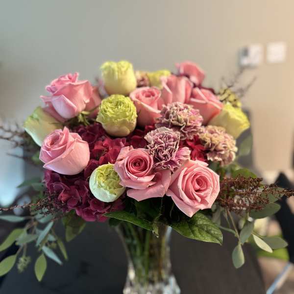 Pink roses and carnations arranged in a clear glass vase