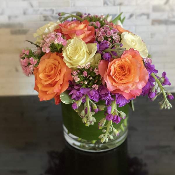 Bouquet of orange, yellow, and purple flowers in a glass vase