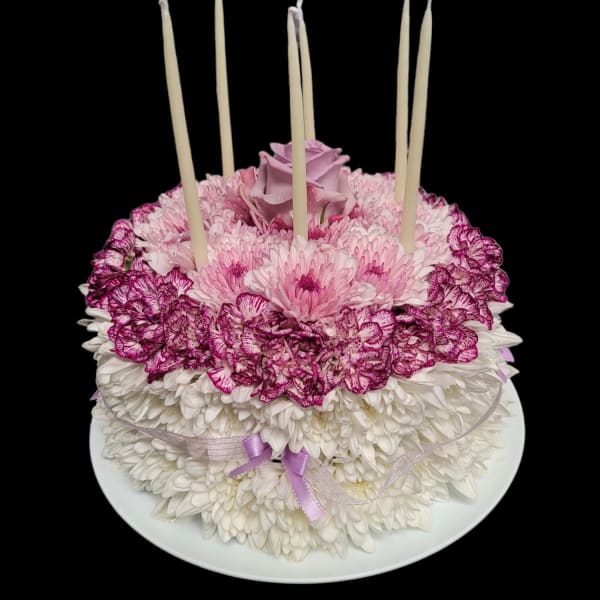 Round floral cake with pink and white flowers and tall candles