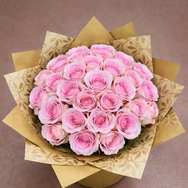 Bouquet of pink roses wrapped in patterned gold paper