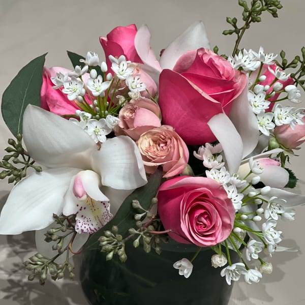 Pink roses and white orchids in a dark vase