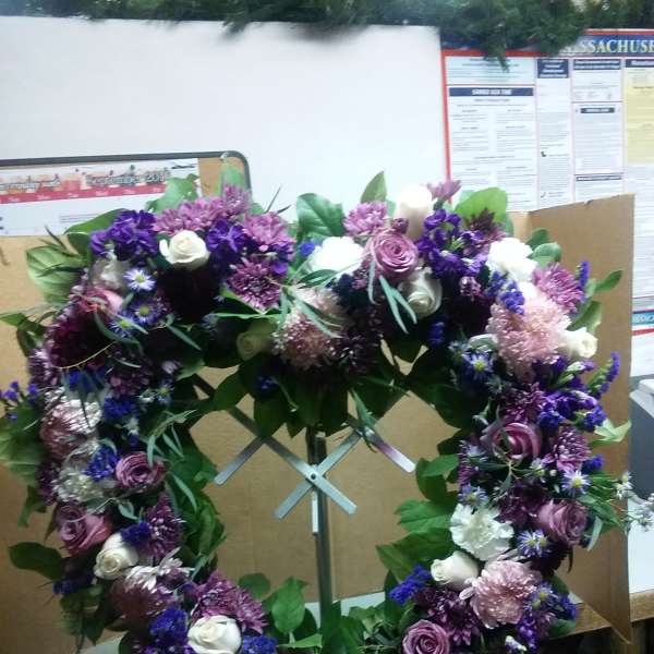 Purple and white floral wreath on a metal stand