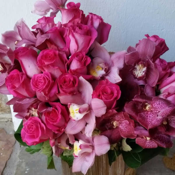Pink roses and orchids arranged in a gold vase