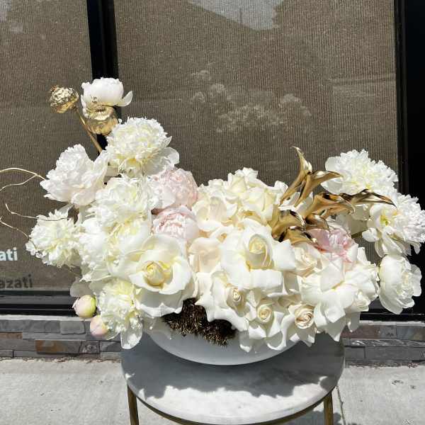 White floral arrangement with roses and peonies in a low bowl