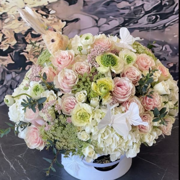 Round bouquet of pale pink and white flowers in a white hat box