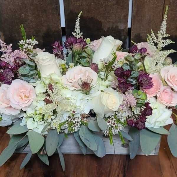 Low floral centerpiece with pink and white roses and purple accents