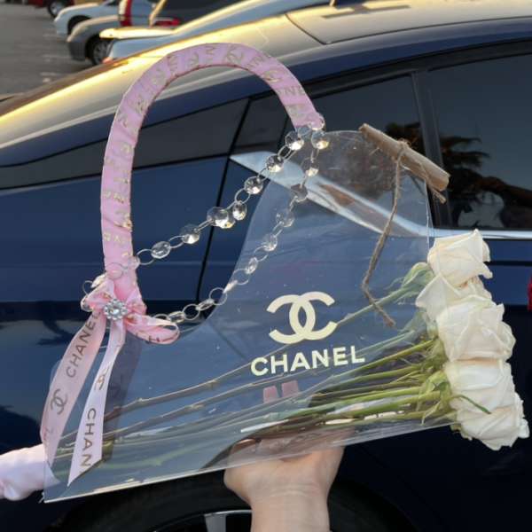 White roses in a clear handbag-shaped gift box with pink ribbon