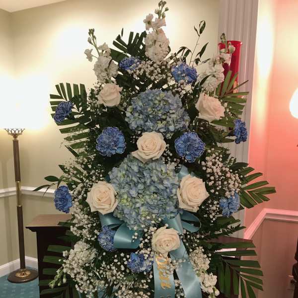 Large blue and white funeral spray with roses and hydrangeas