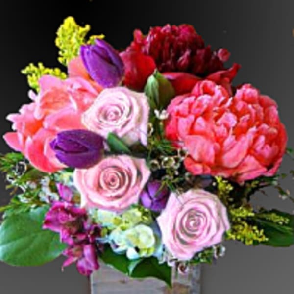 Mixed pink, red, and purple bouquet in a clear square vase