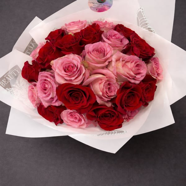 Bouquet of red and pink roses wrapped in white paper